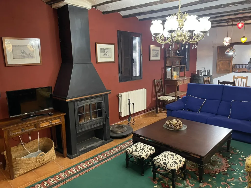 Salón de la fonda con chimenea, sofá y una mesa en medio