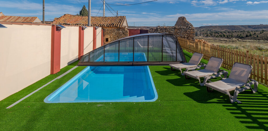 Piscina exterior techada con 3 hamacas y césped artificial alrededor