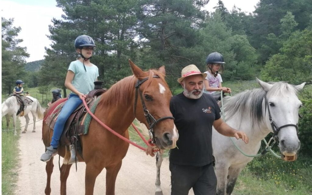 Dos niñas montadas a caballo con el adiestrador