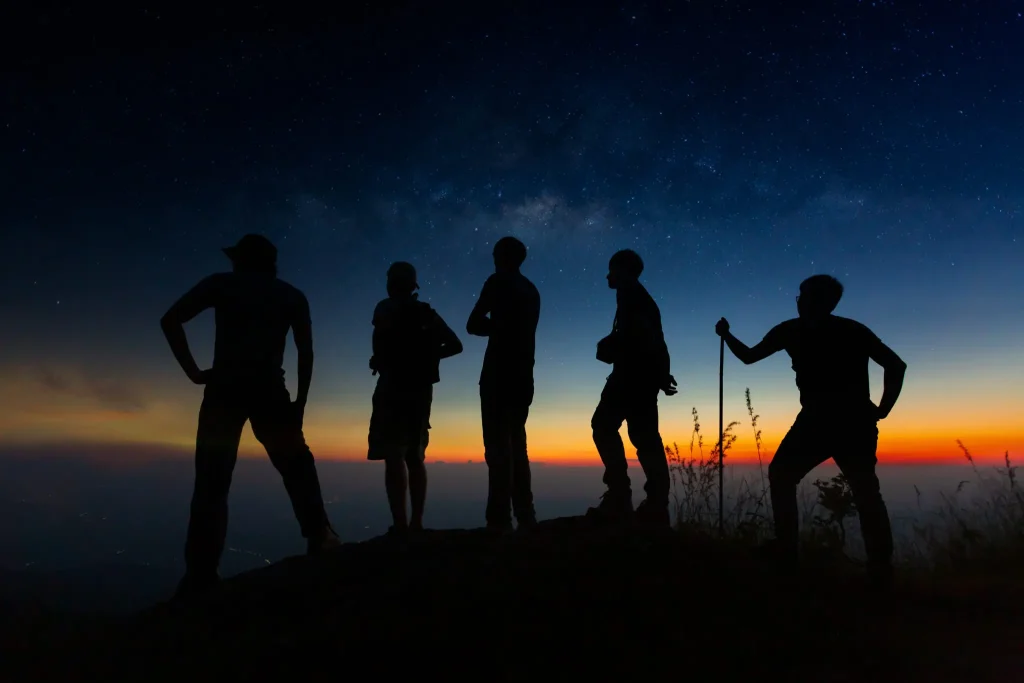 Persona encima de una montaña de noche con cielo estrellado